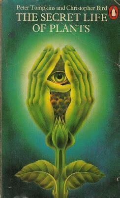 Image ID: A photo of the book The Secret Life of Plants by Peter Tompkins and Christopher Bird. The cover consists of a plant with two human-like hands flowering from the stem, with an eye in the middle. End ID.